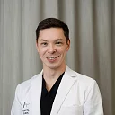 Dr. Kenneth Chiu fra Asteta Clinic, iført hvit frakk foran et nøytralt bakteppe.
