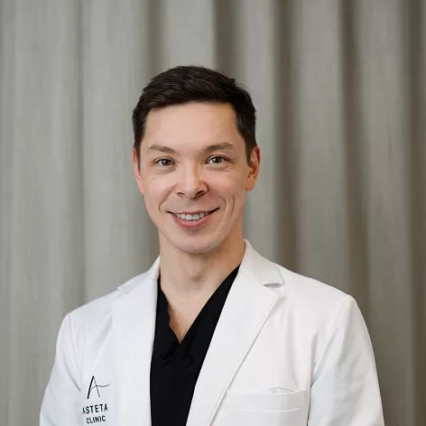 Dr. Kenneth Chiu fra Asteta Clinic, iført hvit frakk foran et nøytralt bakteppe.