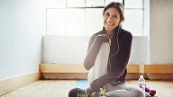 Ung kvinne i treningstøy sitter på yoga matte