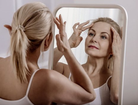 Kvinne ser på panne og hårfeste i speilet