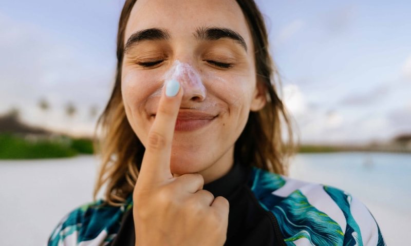 Kvinne smører nesen med solkrem