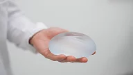 Plastikkirurg hos Asteta Clinic holder et silikon bryst - silikonimplantat