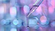 Pipette drypper væske i et laboratoriemiljø med lilla og blålig bokeh-bakgrunn.