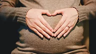 Hender som former et hjerte på en gravid mage